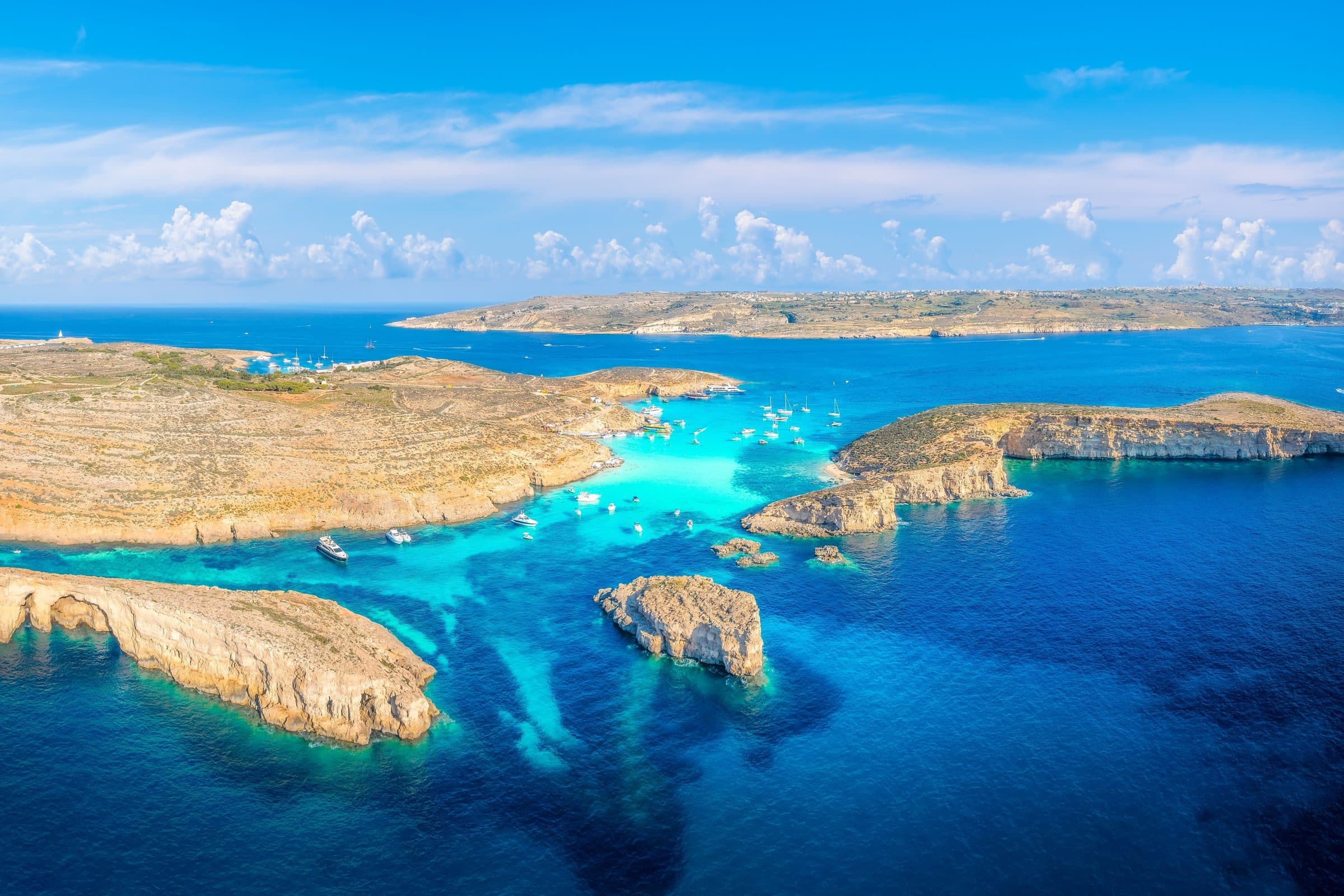 Aerial view of the Blue Lagoon on Comino, with boats on turquoise water and Gozo in the distance